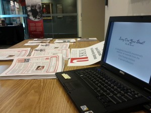 Low angle photograph of laptop, promotional material, on a table at the Archives of Ontario.