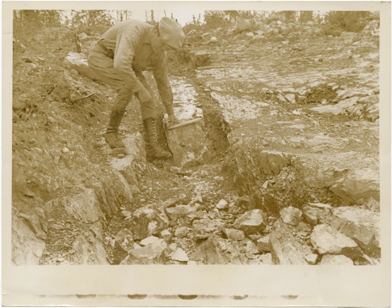 Miner in Canada : Image of man leaning over to work with soil. He is wearing boots and a hate.